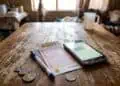 image of a lotto ticket on a table with South African rand coins and a smartphone on a table.